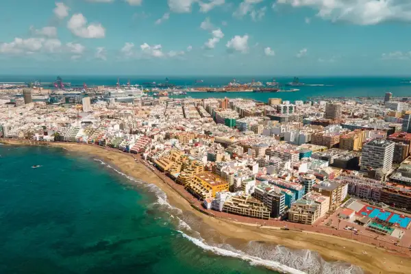Vista aérea de Las Palmas de Gran Canaria, con la playa, el mar turquesa y el puerto al fondo. Descubre qué ver en Las Palmas de Gran Canaria.