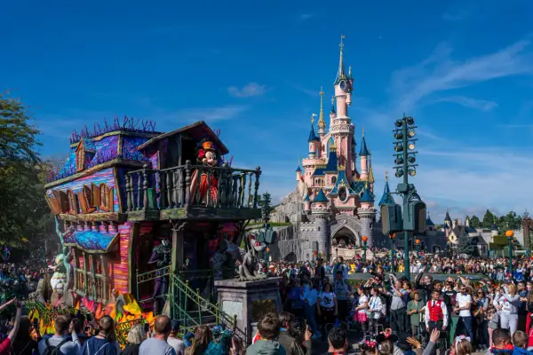 Desfile de **Disneyland Paris Halloween** con Mickey Mouse en un carro espeluznante frente al castillo.