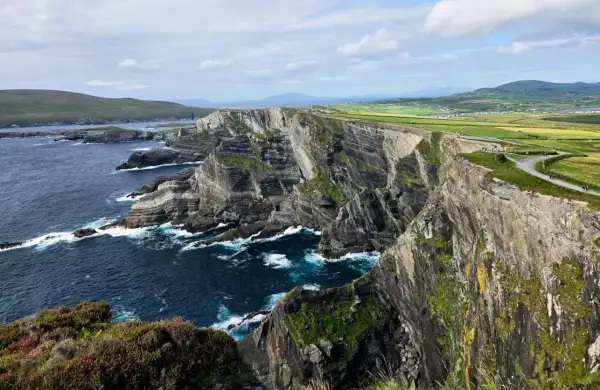 Impresionantes acantilados y el océano Atlántico azul profundo, parte de una ruta por Irlanda. Senderos serpentean por la cima verde.