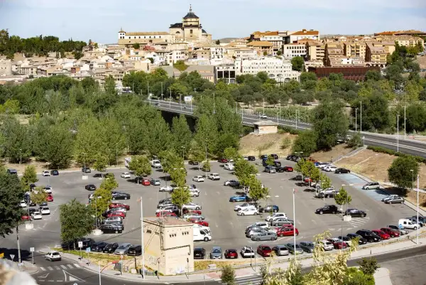 Amplio aparcamiento con muchos coches, ideal para saber donde aparcar en Toledo. Al fondo, la histórica ciudad se alza majestuosa.