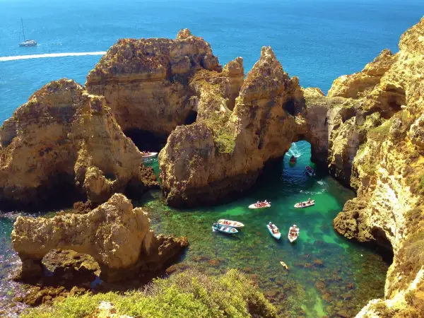 ¡Qué ganas de ir al Algarve en coche! Aquí, barcos exploran cuevas y arcos naturales en aguas cristalinas.