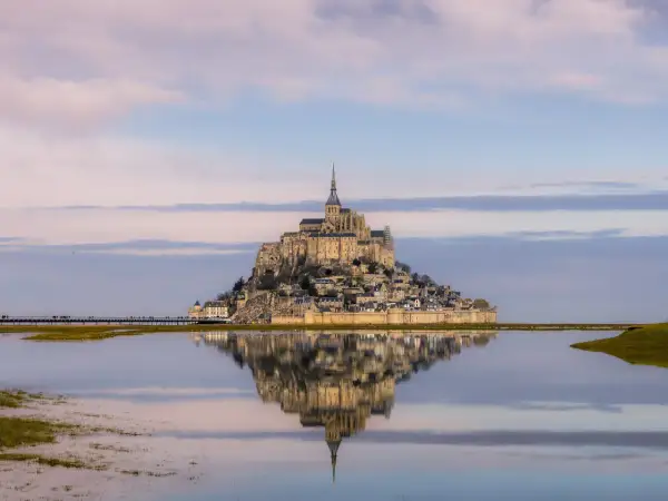 Mont Saint-Michel como llegar: la abadía reflejada en el agua, un sueño al amanecer.