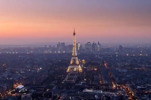 Vista panorámica de París al anochecer, con la Torre Eiffel iluminada y el horizonte de la ciudad. Un recuerdo inolvidable de las visitas a la Torre Eiffel.