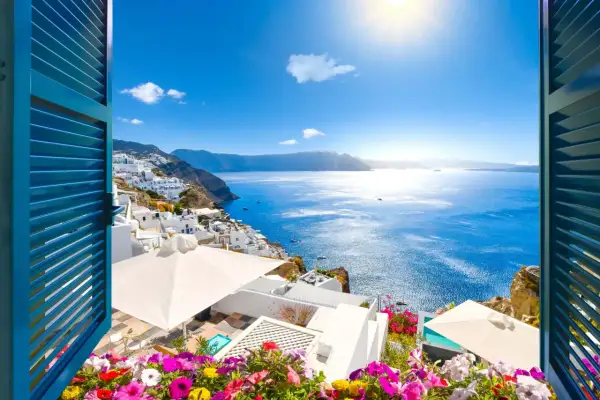 Vista de Santorini, Grecia, con casas blancas en la ladera y el mar azul brillante. ¡Un lugar perfecto donde viajar en junio!