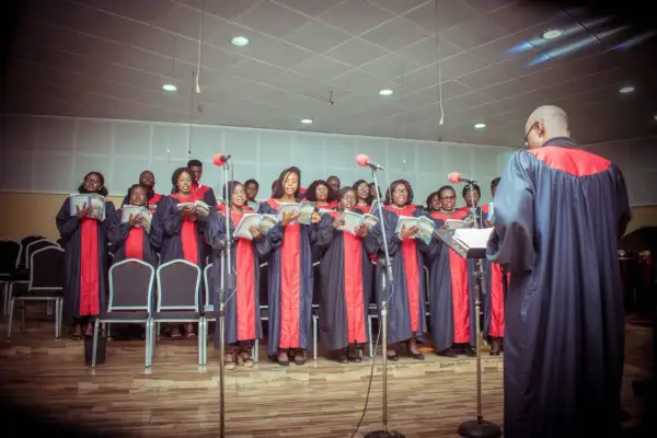 Coro cantando en una misa gospel en Nueva York, con túnicas azules y rojas, leyendo partituras.