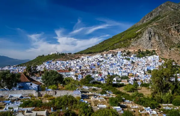 Vista panorámica de Chefchaouen, la ciudad azul, encaramada en una ladera montañosa. A pesar de su belleza, se rumorea que Chefchaouen es peligroso, con un cementerio en primer plano.